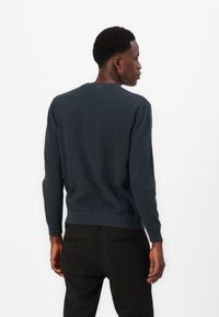 Marineblauer Rundhals-Pullover aus weichem Material, mit gerippten Bündchen und Saum, präsentiert in einem lässigen Schnitt und minimalistischem Design.