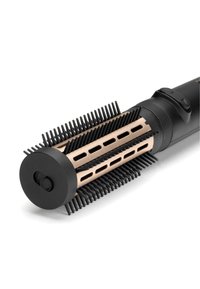 Brosse soufflante rotative avec poils noirs et cylindre métallique doré, montrant partiellement l'interrupteur d'alimentation et la poignée.