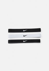 Tri skupine Nike gumice za kosu: jedna potpuno crna, jedna potpuno bijela i jedna crna s bijelim šavovima, sve s malim bijelim Nike logotipom.