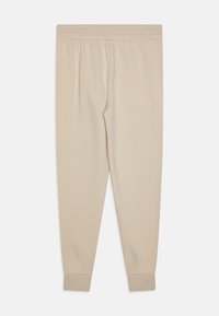 Beige joggerbikses no maiga auduma ar elastīgu jostu un ribotām piedurknēm. Vienkāršs dizains ar gludu tekstūru un bez pamanāmām rakstām vai akcentiem.