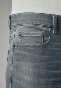 Jeanși din denim gri, cu o croială slim, design cu cinci buzunare, cusături contrastante și un mic buzunar pentru monede în partea din dreapta față.