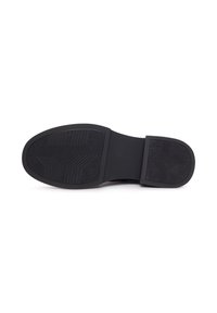 Semelle de chaussure en caoutchouc noir avec des motifs de grip texturés, y compris des lignes angulaires et des encoches pour la traction. Bords lisses et forme arrondie.