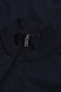 Navy zip-up sweater with a high collar, made of ribbed knit fabric. Features a silver zip pull with a logo. Smooth texture, no patterns.