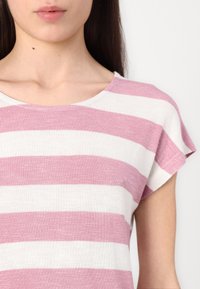 Lett stripete topp med vekslende rosa og hvite horisontale striper, rund hals og korte, utfoldede ermer.
