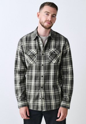 Black and white plaid flannel shirt with a button-up front, two chest pockets, and a soft, textured fabric. Careful pattern alignment visible.