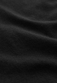 Tessuto nero con una superficie liscia, che presenta leggere pieghe e irregolarità. Sembra morbido e ha una finitura opaca.