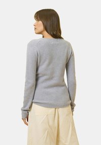 Maglione grigio chiaro realizzato in morbido tessuto a maglia, caratterizzato da maniche lunghe, un collo arrotondato e una silhouette aderente. Texture liscia.