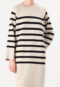 Maglione lavorato a maglia in beige con strisce orizzontali nere. Presenta un collo rotondo e maniche a tre quarti con una vestibilità rilassata.