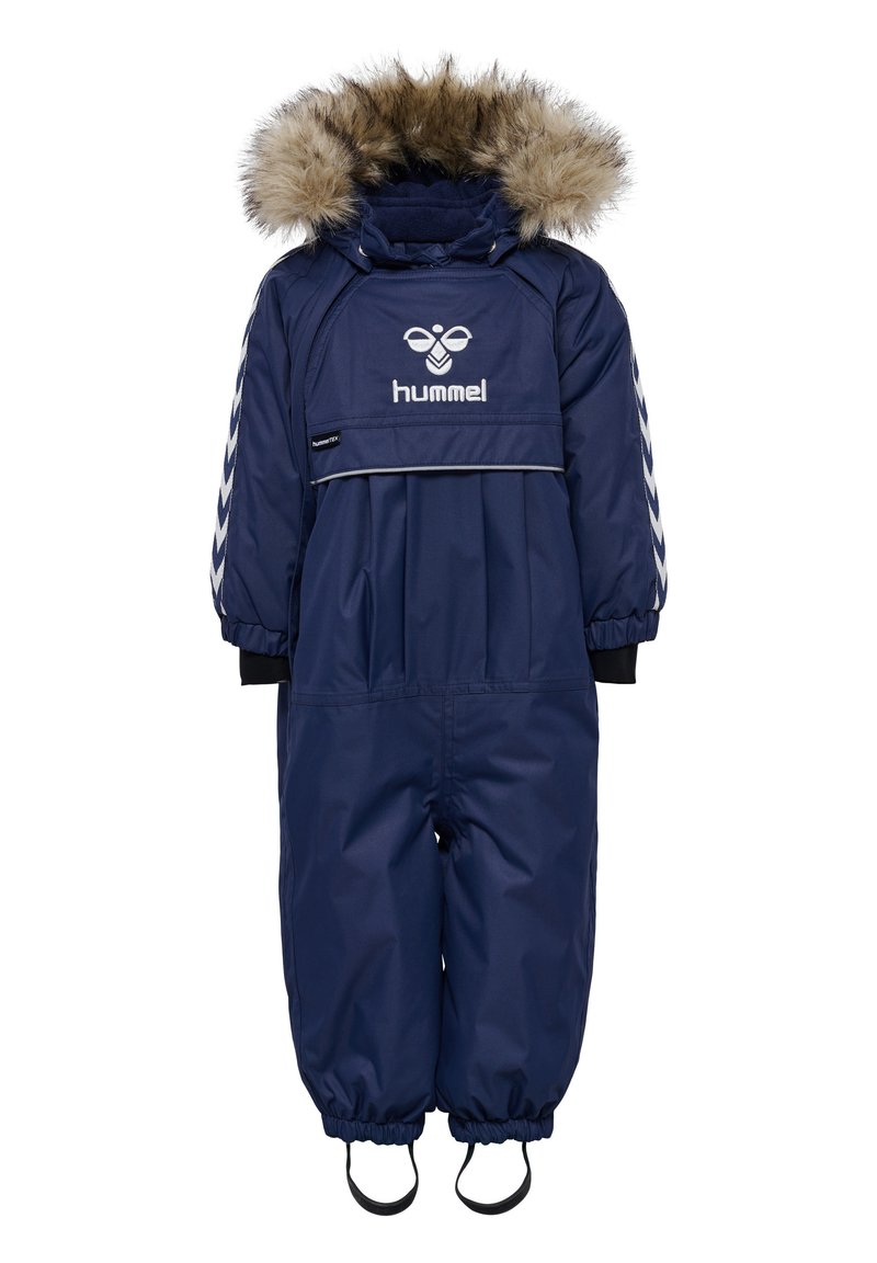Marinblå snödräkt med huva fodrad med fuskpäls, elastiska manschetter och logotyp. Har dragkedja och justerbara stövelremmar för en säker passform.