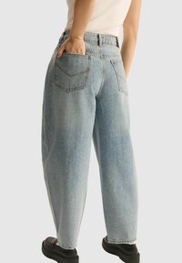 Jasnoniebieskie dżinsy o luźnym kroju, wysokim stanie i dwóch tylnych kieszeniach. Wykończone kontrastowymi przeszyciami i prostym krojem nogawek.
