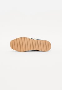 Gummisåle til sneakers i oransjebrun farge, teksturert med horisontale riper for grep og støtte. Øverste kant er svakt avrundet og flat.