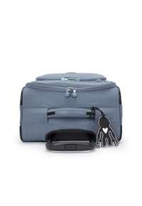 Cestovní kufr o velikosti kabiny, vyrobený z měkkého modrého materiálu, s dvojitými zipy, boční rukojetí, černými akcenty, texturovaným povrchem a štítkem na zavazadla ve tvaru opice.