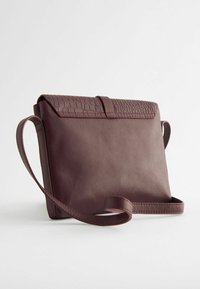 Sac en cuir bordeaux porté crossbody avec un motif reptile texturé sur le rabat, équipé d'une longue sangle ajustable et d'une finition lisse.