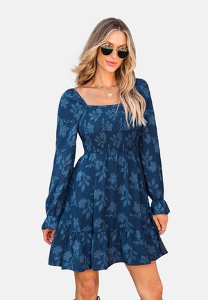 Donkerblauwe jurk met vierkante halslijn, lange mouwen en geplooide bustier. Kenmerkt een bloementextuur patroon en een gerimpelde zoom.