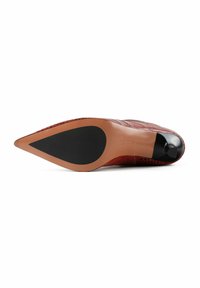 Escarpin rouge à bout pointu avec une tige texturée ressemblant à de la peau de crocodile. Semelle lisse couleur beige avec un insert en caoutchouc noir au talon.