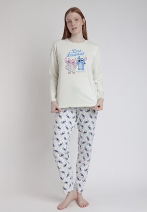 Camisa de pijama de manga larga en crema con estampado de animales de dibujos animados; combinada con pantalones blancos que presentan un patrón colorido de animales y finas rayas verticales.