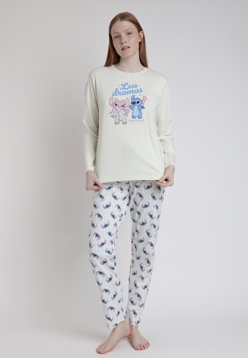 Camisa de pijama de manga larga en crema con estampado de animales de dibujos animados; combinada con pantalones blancos que presentan un patrón colorido de animales y finas rayas verticales.