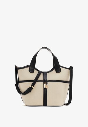 Bolso de lona beige con asas de cuero negro, detalles, correa de hombro ajustable y correa central con un pequeño candado dorado.