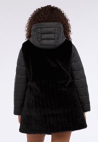 Chaqueta acolchada negra con espalda de piel negra texturizada y capucha acolchada. De longitud corta con un acabado suave y liso. Detalle de cremallera en la cintura.