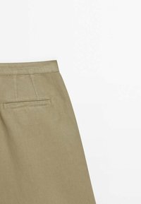 Beige puuvillahame suoran leikkauksen kanssa, jossa on takatasku ja huomaamattomat kirjontavyöt. Sujuva pinta matta viimeistelyllä.