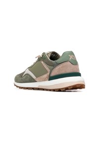 Zapatilla deportiva verde y beige con parte superior de ante texturizado, detalles de tela, mediasuela blanca acolchada y suela exterior marrón resistente.