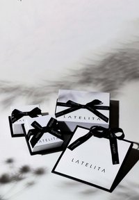 Three white gift boxes with black accents and bows, featuring the brand name "LATELITA" in black text on the front.
