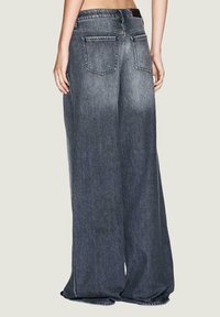 Jeans de mezclilla de pierna ancha en un lavado oscuro con una textura suave, que cuentan con dos bolsillos traseros y detalles de dobladillo deshilachado.