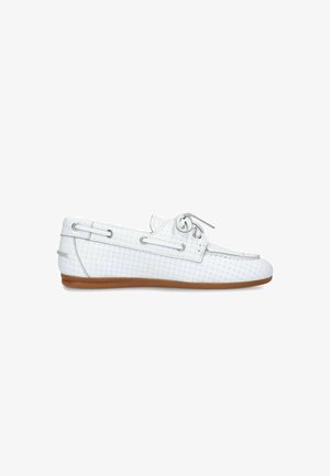 Witte geweven leren loafer met zijstrikdetail en bruine platte rubberen zool, getoond in profiel tegen een witte achtergrond.