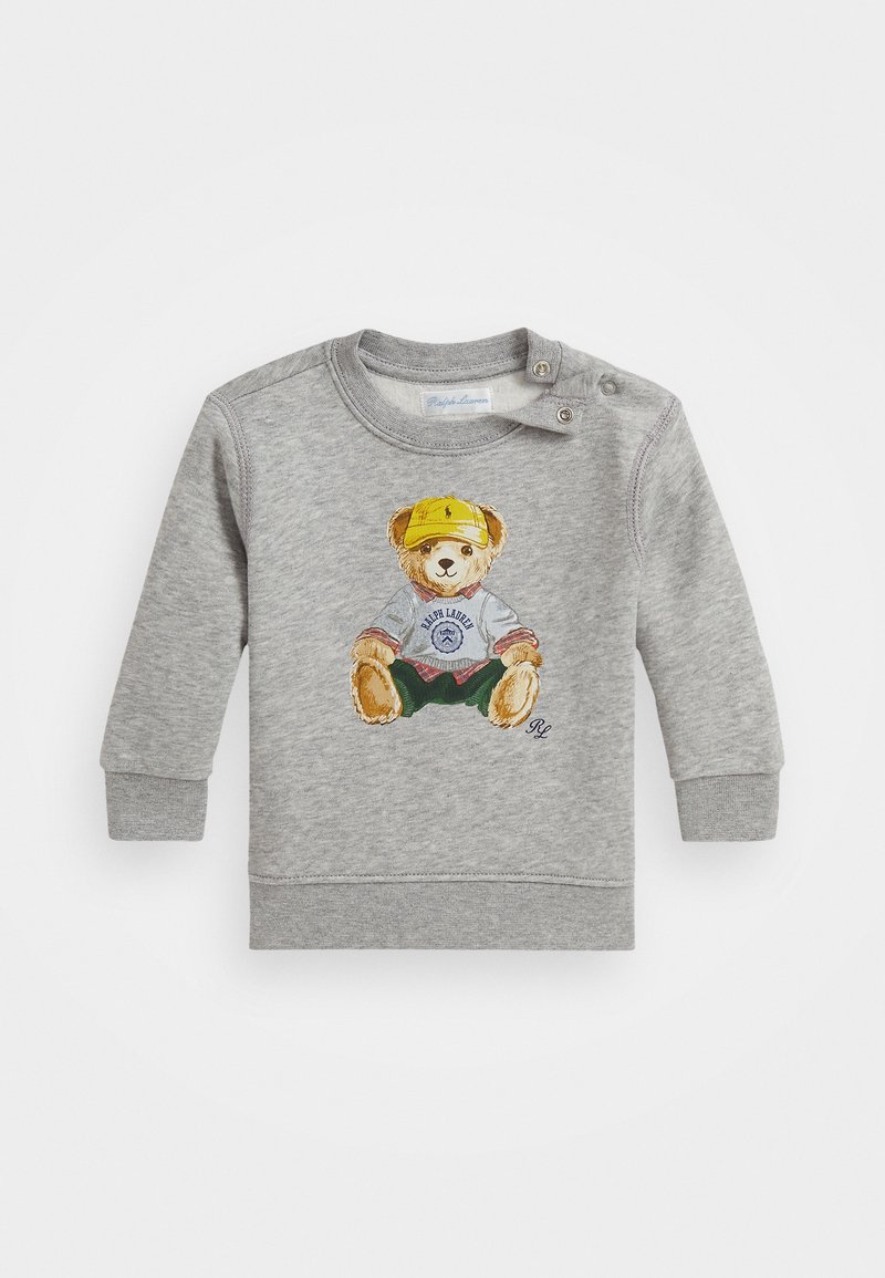 T-shirt bébé gris à manches longues avec un ours en peluche portant une casquette jaune et des vêtements décontractés imprimés sur le devant, avec des boutons-pression à l'épaule.