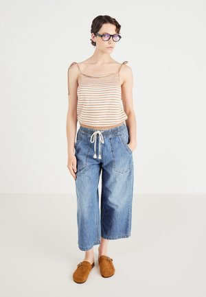 Stripet strikket topp med knytte stropper, løse denim culotter med elastisk midje, og brune semskede slip-on sko. Avslappet antrekk.