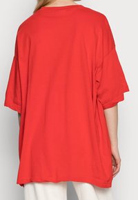 T-shirt oversize rossa realizzata in cotone morbido, con scollatura rotonda e maniche corte, caratterizzata da un fit ampio e rilassato e una texture liscia.