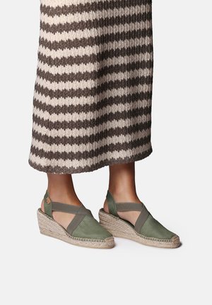 Rohelised lõuendist espadrille-klotskontsad ristkihtdetailiga, jootud tallad ja kummikatted, kombineeritud triibulise kootud seelikuga.