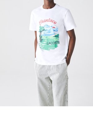 T-shirt en coton blanc ornée d'un graphique coloré avec des arbres et un coucher de soleil, assortie à un pantalon décontracté noir et blanc à rayures.
