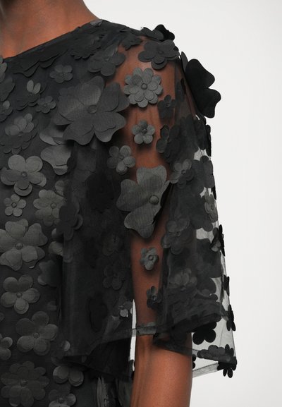 Sorte gennemsigtige kjole med blomstermønster, fremstillet af lagdelt stof med hævede sorte blomsterapplikationer, korte ærmer og rund halsudskæring.