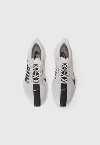 Une paire de chaussures de course Nike Flyknit légères grises et noires vue de dessus sur un fond blanc.