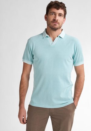 Helles blaues Polohemd mit kurzem Kragen und V-Ausschnitt, aus weichem Stoff, kombiniert mit beigen Hosen, zeigt eine lässige Passform.
