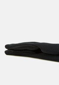 Gants noirs en tissu texturé, avec une paume lisse et des bords cousus, présentés en position pliée sur un fond blanc.