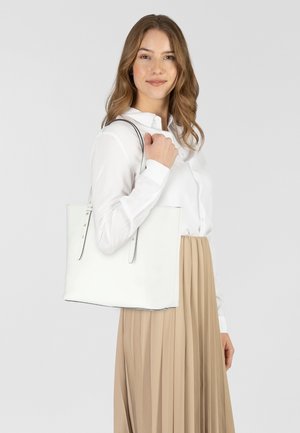 Sac fourre-tout en cuir blanc avec un design épuré, une texture douce, des bretelles doubles, et des accents minimalistes. Présenté sur un fond clair.