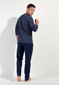 Navy blue loungewear set featuring a patterned long-sleeve top and solid pants. Relaxed fit with soft fabric and subtle texture.