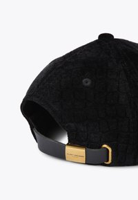Casquette noire texturée en matériau velouté avec une sangle en cuir et une boucle métallique dorée. L'intérieur est orné d'un motif subtil.