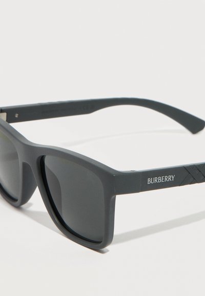 Μαύρα γυαλιά ηλίου Burberry με ορθογώνιους φακούς και ματ σκελετό, με το όνομα της μάρκας στο πλευρικό μπράτσο.