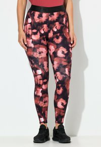 Leggings met hoge taille in een zwart-roze abstract patroon, gemaakt van rekbare stof met een gladde textuur, gecombineerd met zwarte sneakers.