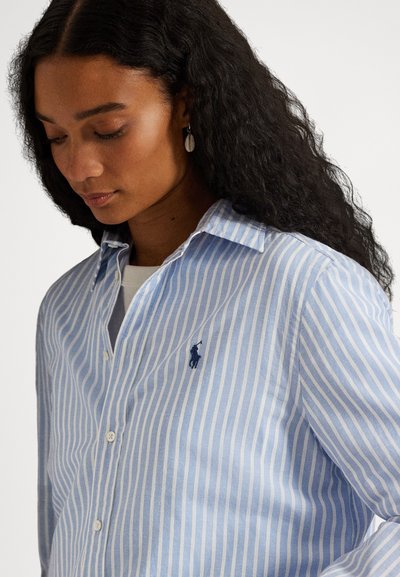 Πουκάμισο με κουμπιά σε ανοιχτό γαλάζιο και λευκές ρίγες, με γιακά, που διαθέτει μικρό σκοτεινό λογότυπο στο στήθος και ελαφρώς υφασμένο ύφασμα.