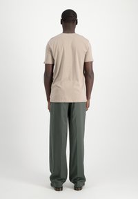 Camiseta de algodón beige con mangas cortas, escote redondo y corte relajado, combinada con pantalones de pierna ancha en verde oscuro de una tela suave.