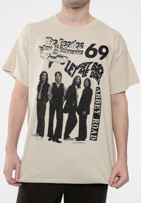 Beige cotton t-shirt featuring a black graphic of four male figures and text related to "The Beatles." Includes a submarine illustration and year 1969.