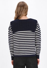 Maglione a righe blu navy e bianco con yoke in lavorazione a treccia solida e testurizzata. Presenta maniche lunghe e una vestibilità morbida.