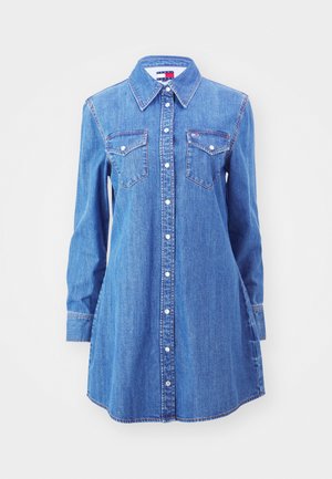 Vestido de camisa de mezclilla en azul claro con mangas largas, frente de botones, dos bolsillos en el pecho y un collar clásico. Presenta detalles de costura sutiles.