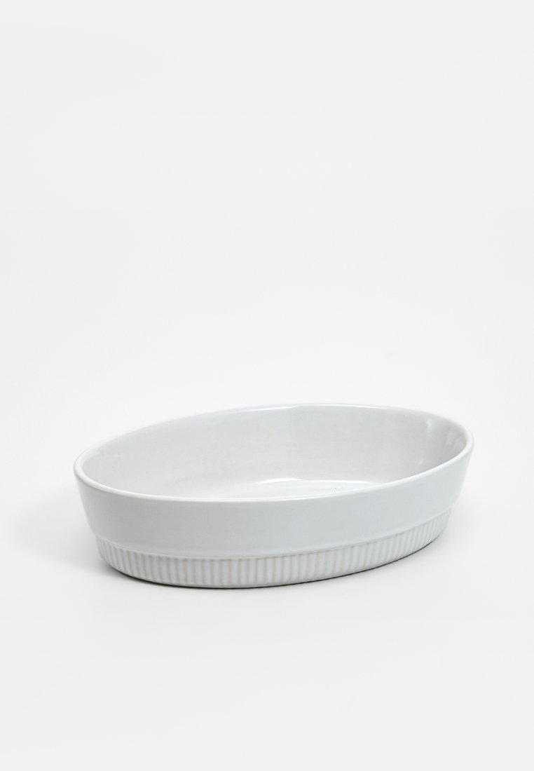 Piatto ovale in ceramica bianca con interni lisci e un design esterno rigato. Forma elegante e poco profonda, adatta per la cottura o per servire.