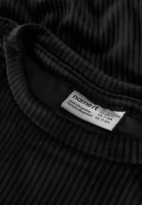 Zwart geribd stof met een ronde hals en een kledinglabel waarop maat- en herkomstgegevens staan vermeld.