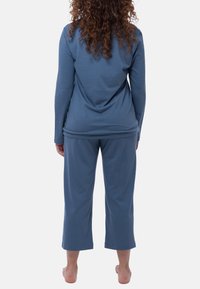 Sininen pitkähihaisuus paita ja lyhyet housut pehmeästä kankaasta, rento istuvuus ja minimaaliset saumat mukavuutta varten.